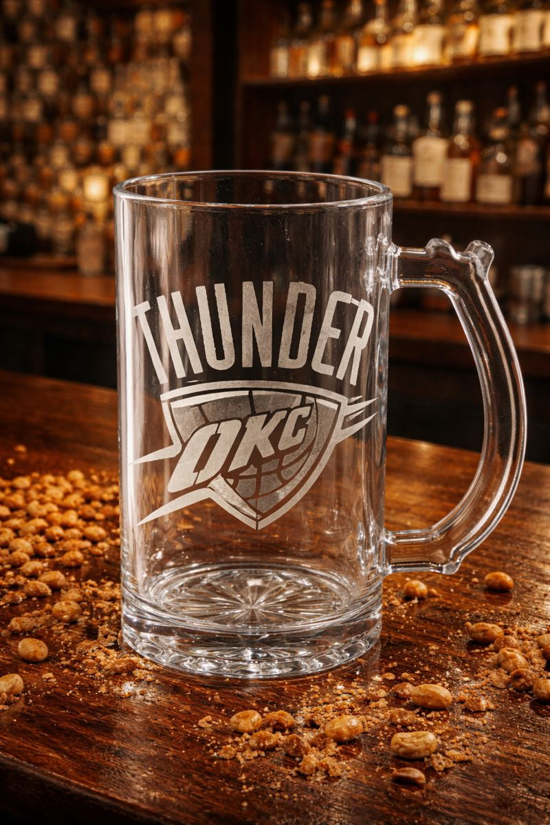 Clear glass mug with 'Thunder OKC' engraving on a wooden surface with snacks.